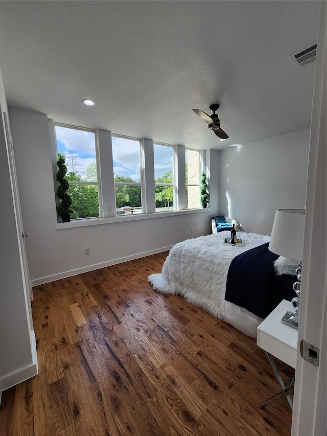 bedroom featuring dark hardwood / wood-style flooring, a textured ceiling, and ceiling fan