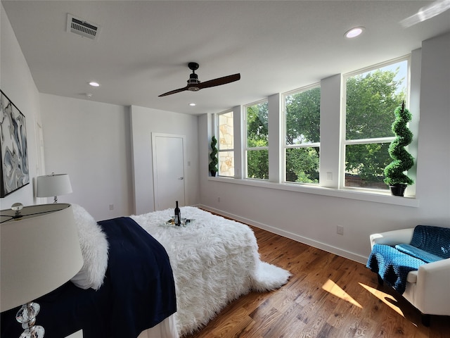 bedroom with ceiling fan, hardwood / wood-style flooring, and multiple windows