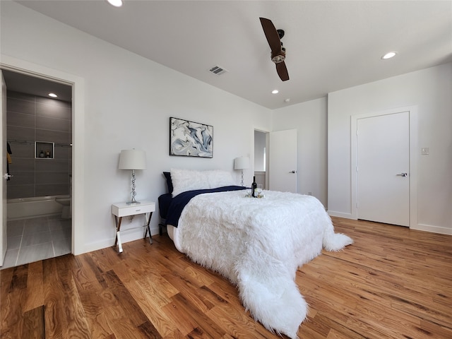 bedroom with ceiling fan, ensuite bathroom, and hardwood / wood-style floors