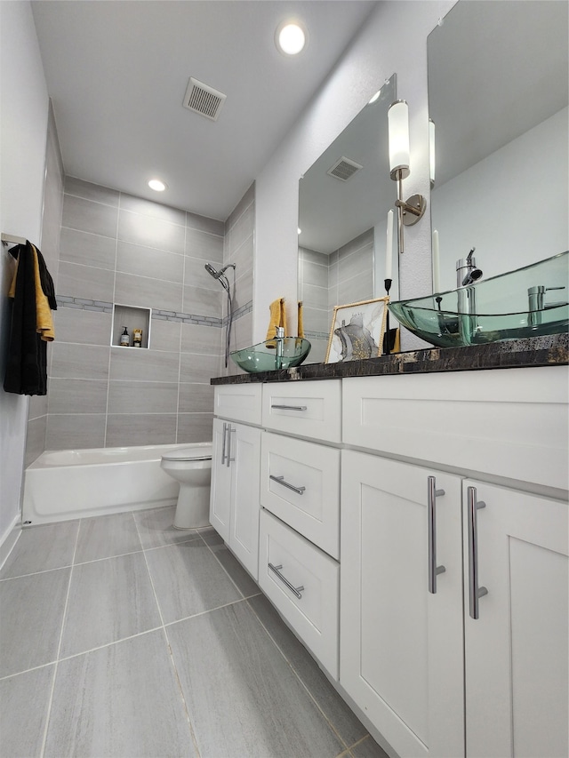 full bathroom with tile patterned flooring, tiled shower / bath, vanity, and toilet