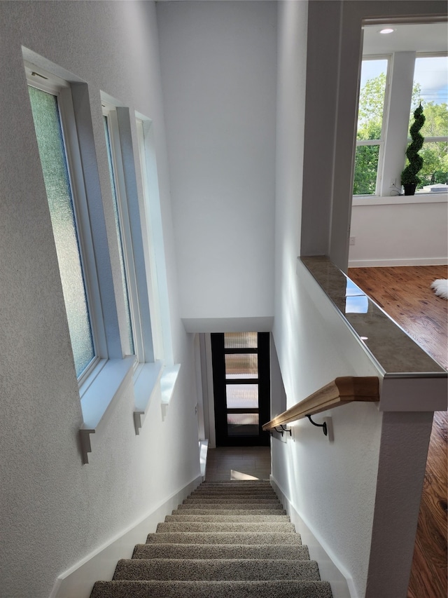 stairway with a wealth of natural light and wood-type flooring