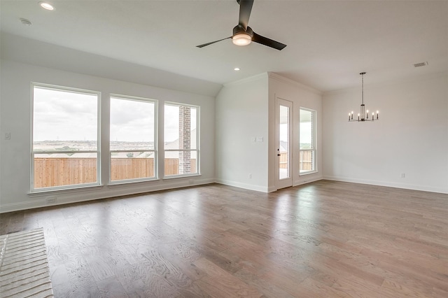 unfurnished room with plenty of natural light, ceiling fan with notable chandelier, crown molding, and light wood-type flooring