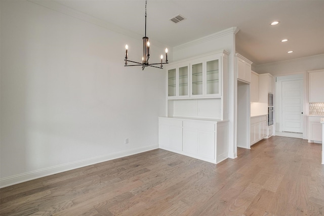 unfurnished dining area featuring a notable chandelier, crown molding, and light hardwood / wood-style floors