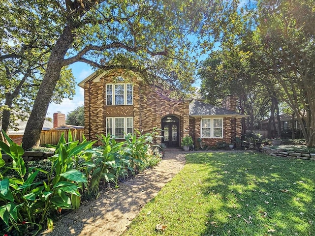 traditional-style home featuring french doors, a front yard, fence, and brick siding