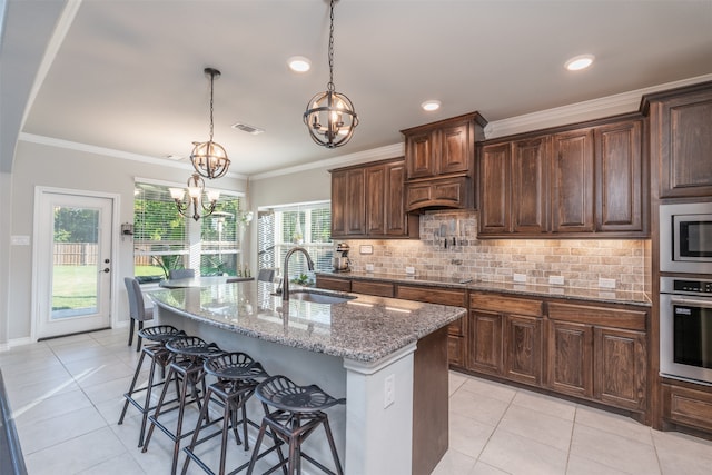 kitchen featuring a center island with sink, a breakfast bar area, appliances with stainless steel finishes, and light stone countertops