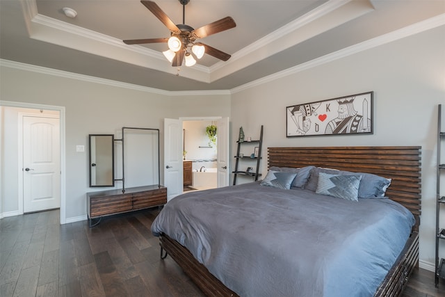 bedroom with ceiling fan, a tray ceiling, dark wood-type flooring, ornamental molding, and connected bathroom