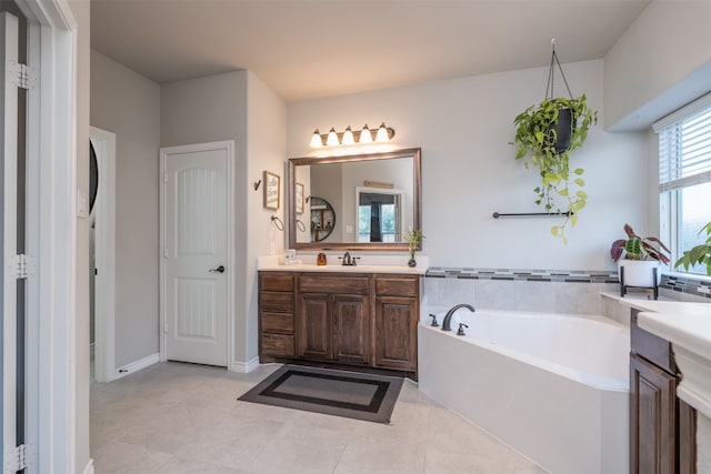 bathroom with tile patterned floors, a tub to relax in, and vanity