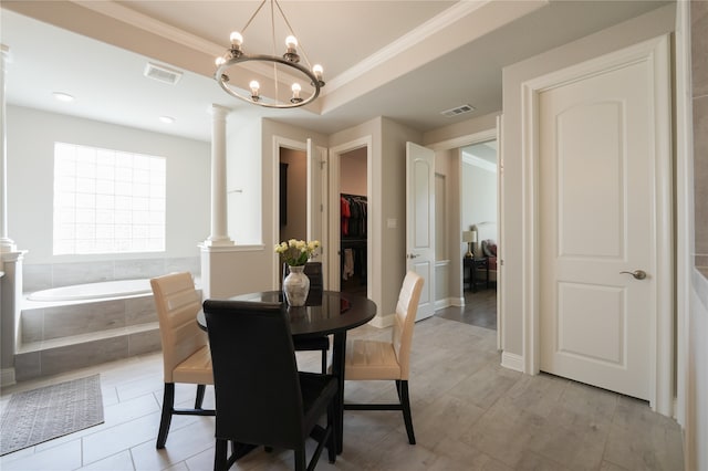 dining room with a tray ceiling, crown molding, ornate columns, and a chandelier