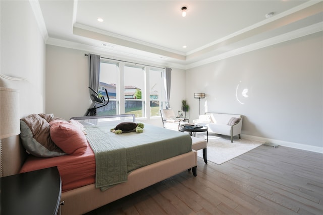 bedroom featuring a tray ceiling, crown molding, and hardwood / wood-style floors