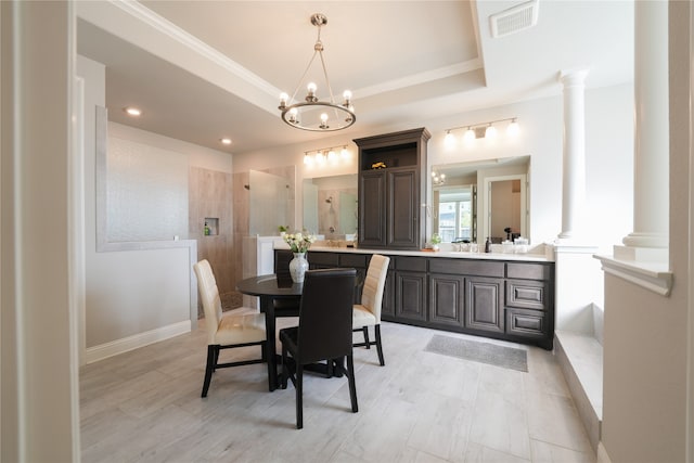 dining room with a chandelier, a tray ceiling, and decorative columns