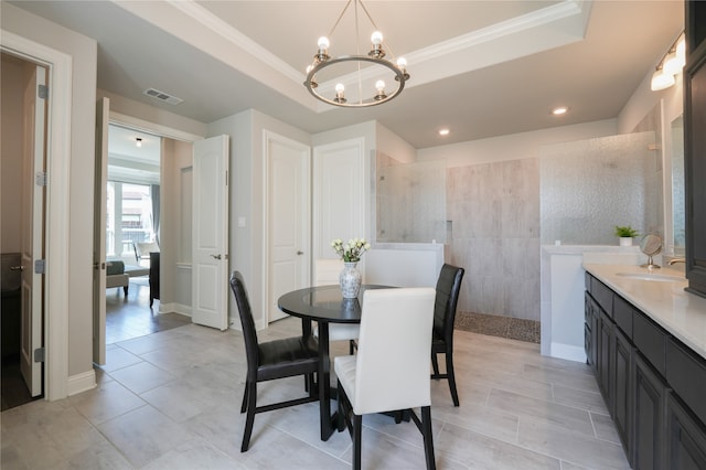 dining room with a tray ceiling, a notable chandelier, and sink