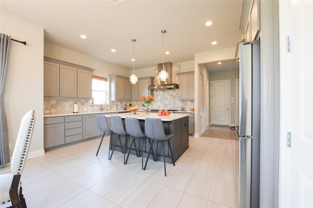 kitchen with wall chimney exhaust hood, tasteful backsplash, a kitchen island, and a breakfast bar