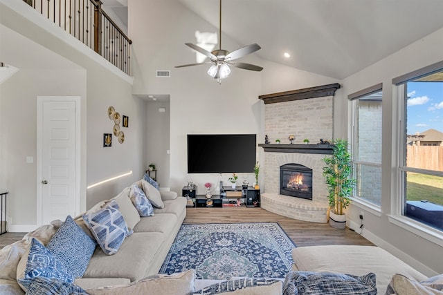 living area featuring a fireplace, visible vents, ceiling fan, wood finished floors, and baseboards