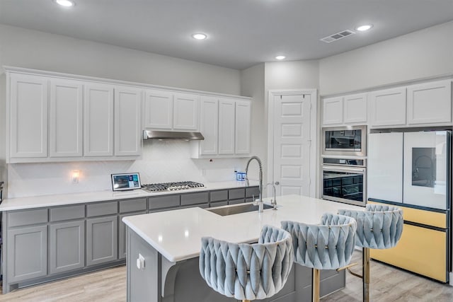 2104 Devonblue Dr, Forney, TX 75126 - kitchen with appliances with stainless steel finishes, a sink, gray cabinetry, light wood finished floors, and recessed lighting