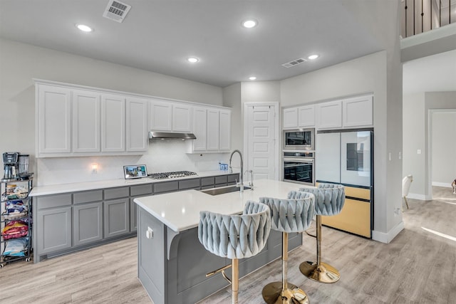 2104 Devonblue Dr, Forney, TX 75126 - kitchen featuring a sink, gray cabinets, stainless steel appliances, under cabinet range hood, and light wood-style floors