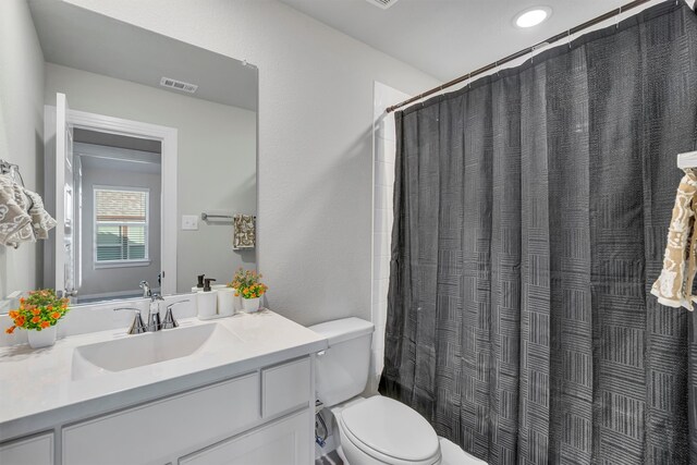 bathroom featuring toilet, vanity, visible vents, and a shower with curtain