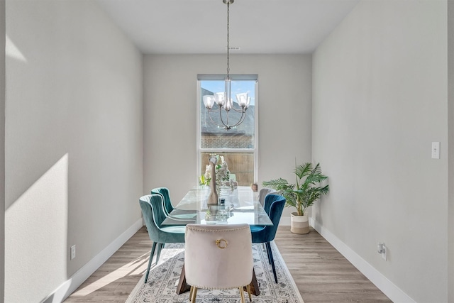 dining area with light wood finished floors, an inviting chandelier, and baseboards