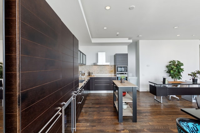 kitchen featuring stainless steel appliances, dark wood-type flooring, decorative backsplash, and wall chimney exhaust hood