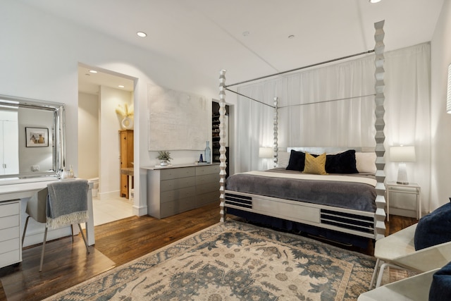 bedroom with connected bathroom and hardwood / wood-style floors