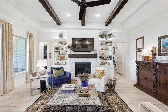 living room featuring ceiling fan, light wood-type flooring, beam ceiling, and a stone fireplace