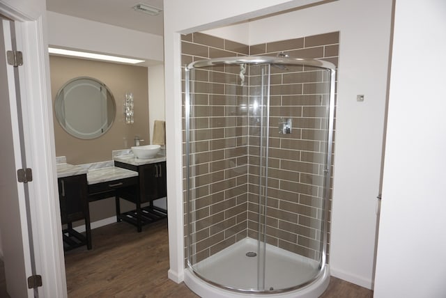 bathroom with a shower with door, hardwood / wood-style floors, and vanity