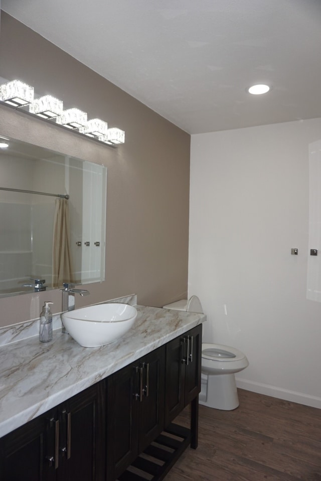 bathroom with hardwood / wood-style floors, a shower with shower curtain, vanity, and toilet