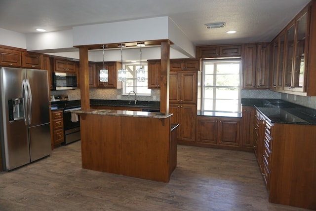 kitchen with dark stone countertops, sink, dark hardwood / wood-style floors, appliances with stainless steel finishes, and a center island