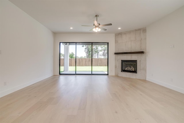 unfurnished living room featuring ceiling fan, light wood-type flooring, and a tile fireplace