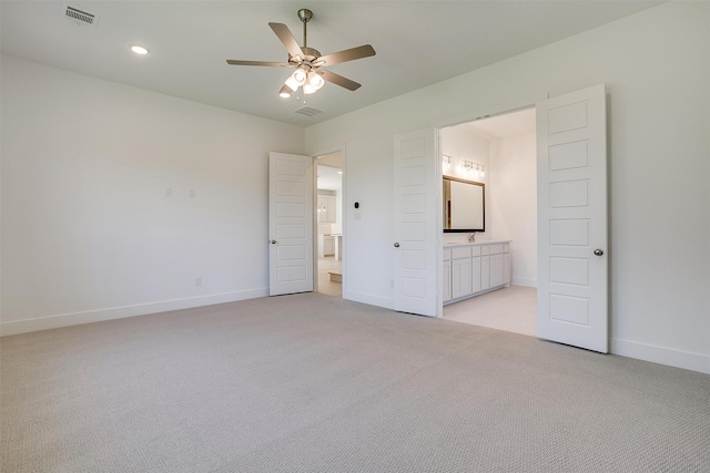 unfurnished bedroom with ceiling fan, light carpet, and ensuite bath