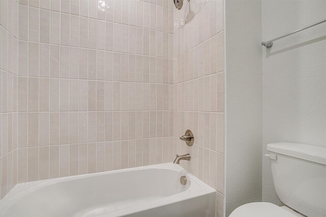 bathroom featuring tiled shower / bath and toilet