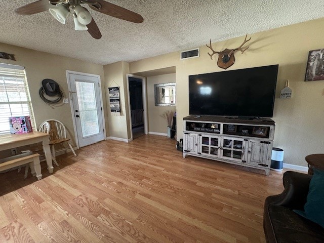 living room featuring a textured ceiling, light wood-type flooring, and ceiling fan