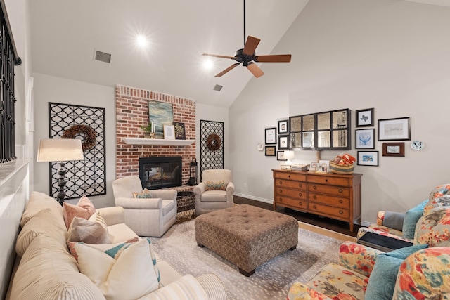 living room with ceiling fan, a brick fireplace, high vaulted ceiling, and hardwood / wood-style flooring