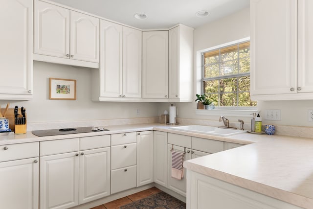 kitchen featuring black electric cooktop, dark tile patterned flooring, sink, and white cabinets