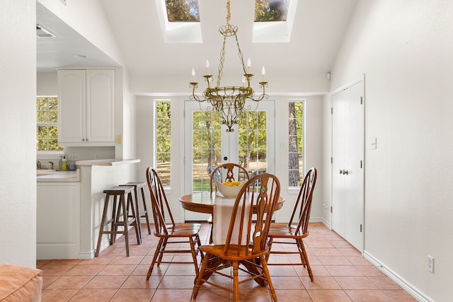 dining room featuring a notable chandelier, vaulted ceiling with skylight, and light tile patterned floors