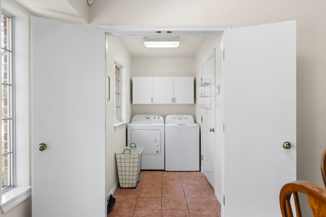 clothes washing area featuring washing machine and dryer, cabinets, and light tile patterned floors