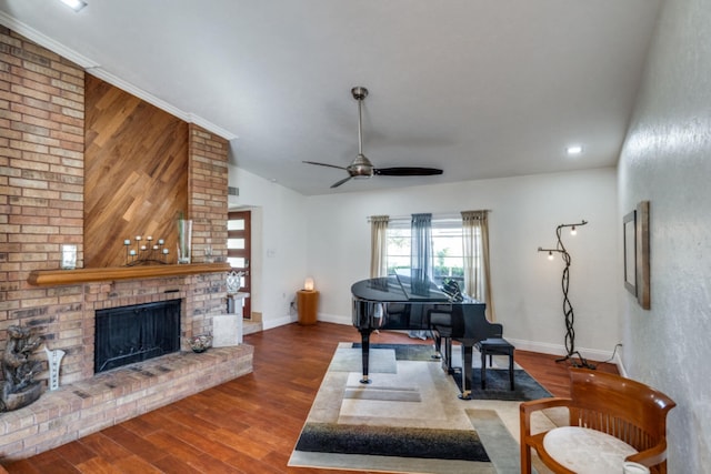 living room featuring ceiling fan, wood-type flooring, vaulted ceiling, a fireplace, and ornamental molding