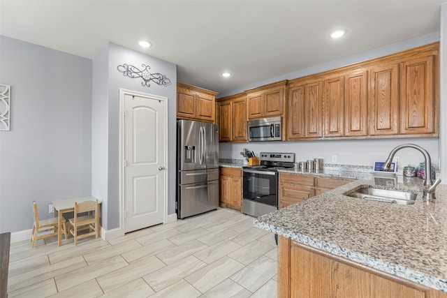 kitchen featuring stainless steel appliances, sink, and light stone counters