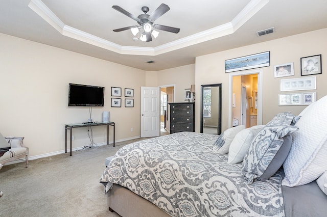 bedroom with ensuite bath, light carpet, ornamental molding, ceiling fan, and a raised ceiling