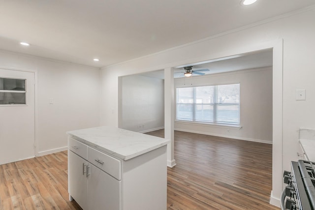 kitchen featuring white cabinetry, ornamental molding, stainless steel range, ceiling fan, and light hardwood / wood-style flooring