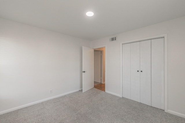 unfurnished bedroom featuring light colored carpet and a closet