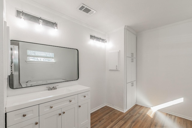 bathroom with hardwood / wood-style flooring, ornamental molding, and vanity