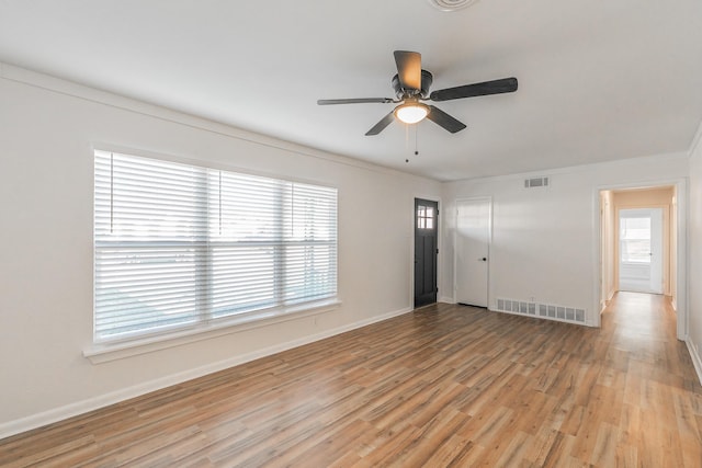 empty room featuring ceiling fan, crown molding, a healthy amount of sunlight, and light wood-type flooring