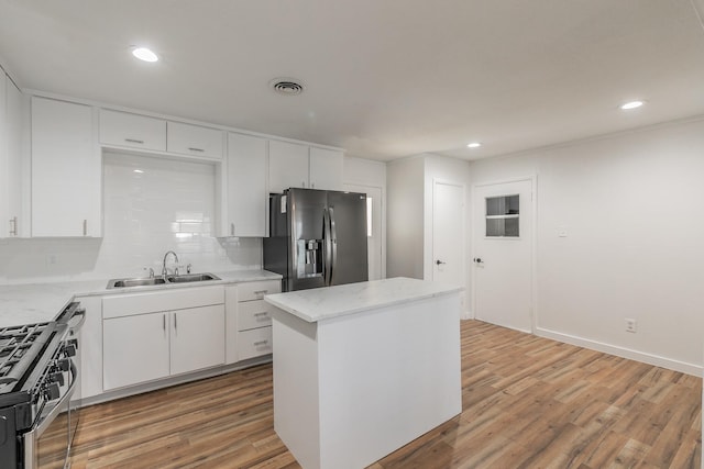 kitchen with sink, white cabinetry, hardwood / wood-style flooring, stainless steel appliances, and backsplash