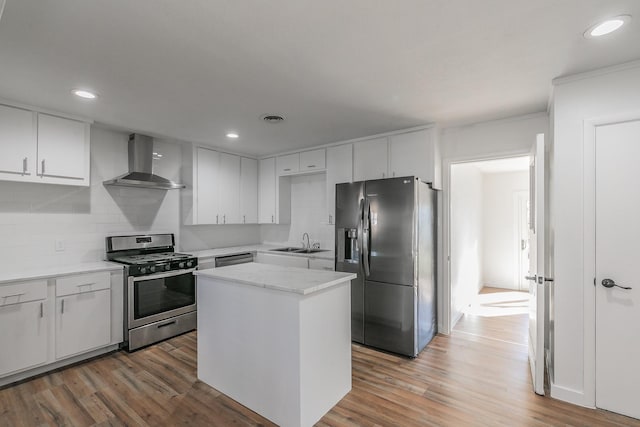 kitchen featuring appliances with stainless steel finishes, a center island, white cabinets, and wall chimney exhaust hood