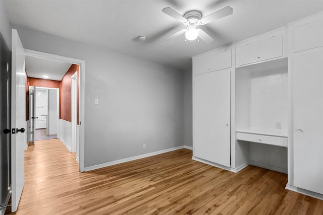 unfurnished bedroom featuring built in desk, light hardwood / wood-style flooring, a closet, and ceiling fan