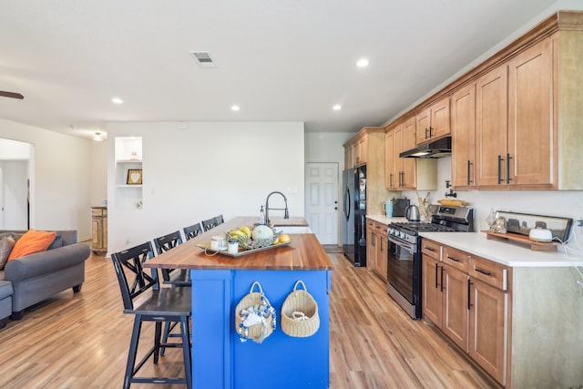 kitchen featuring a kitchen bar, gas range, light wood-type flooring, and sink