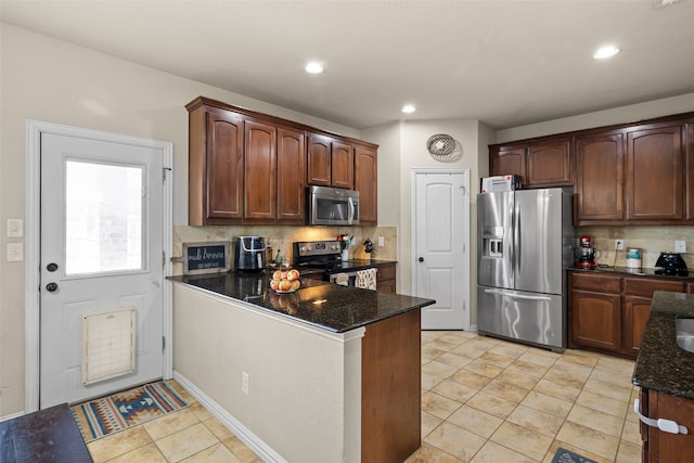 kitchen featuring kitchen peninsula, dark stone counters, decorative backsplash, and stainless steel appliances