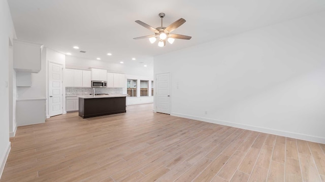 unfurnished living room with sink, light hardwood / wood-style flooring, and ceiling fan