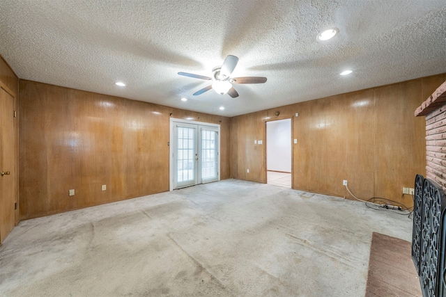 spare room featuring a fireplace, light carpet, a textured ceiling, and ceiling fan