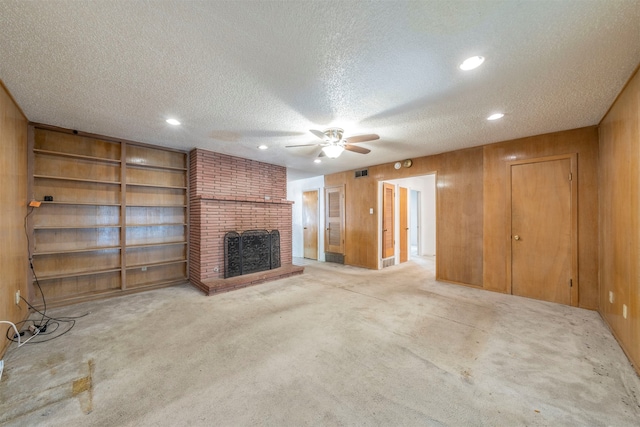 unfurnished living room featuring a textured ceiling, light colored carpet, and wood walls